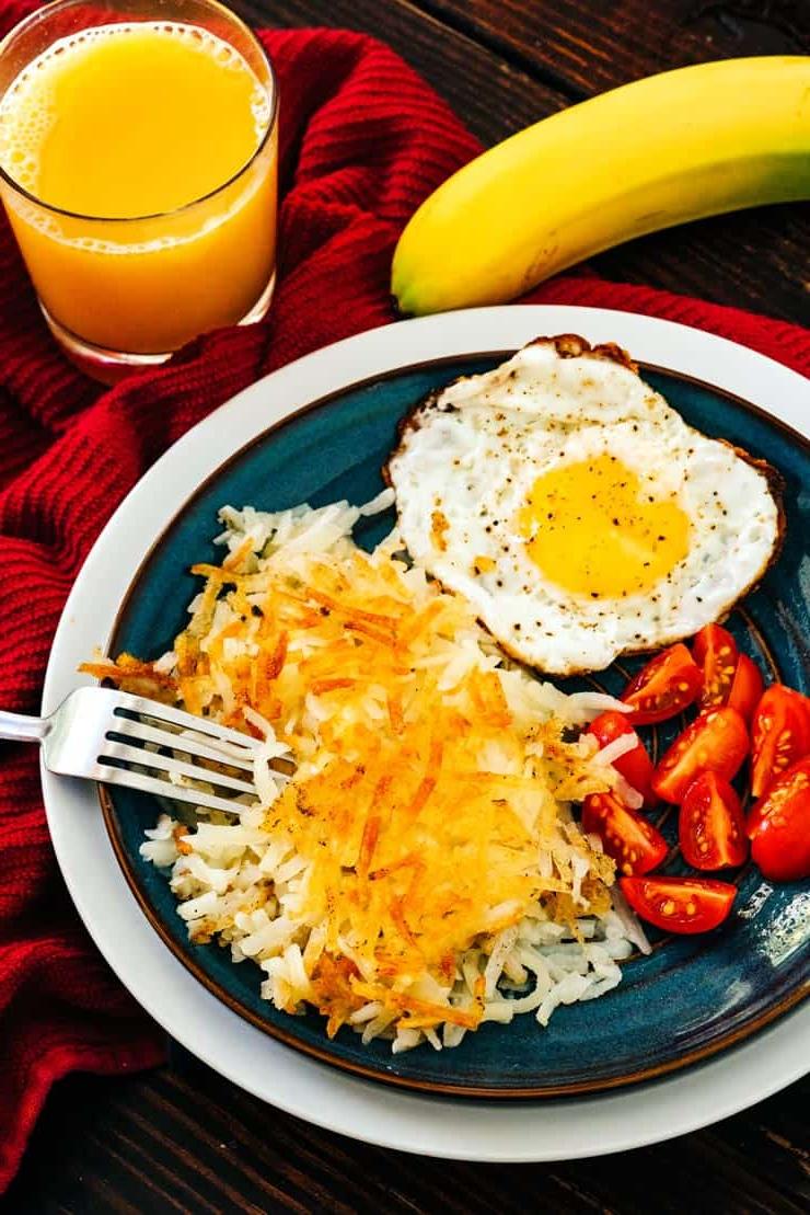 Hashbrowns Fatti in Casa su un piatto con uovo fritto e pomodori