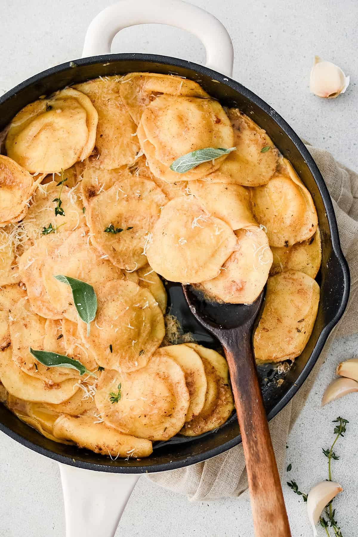 Ravioli al burro nocciola e aglio in una padella con un cucchiaio