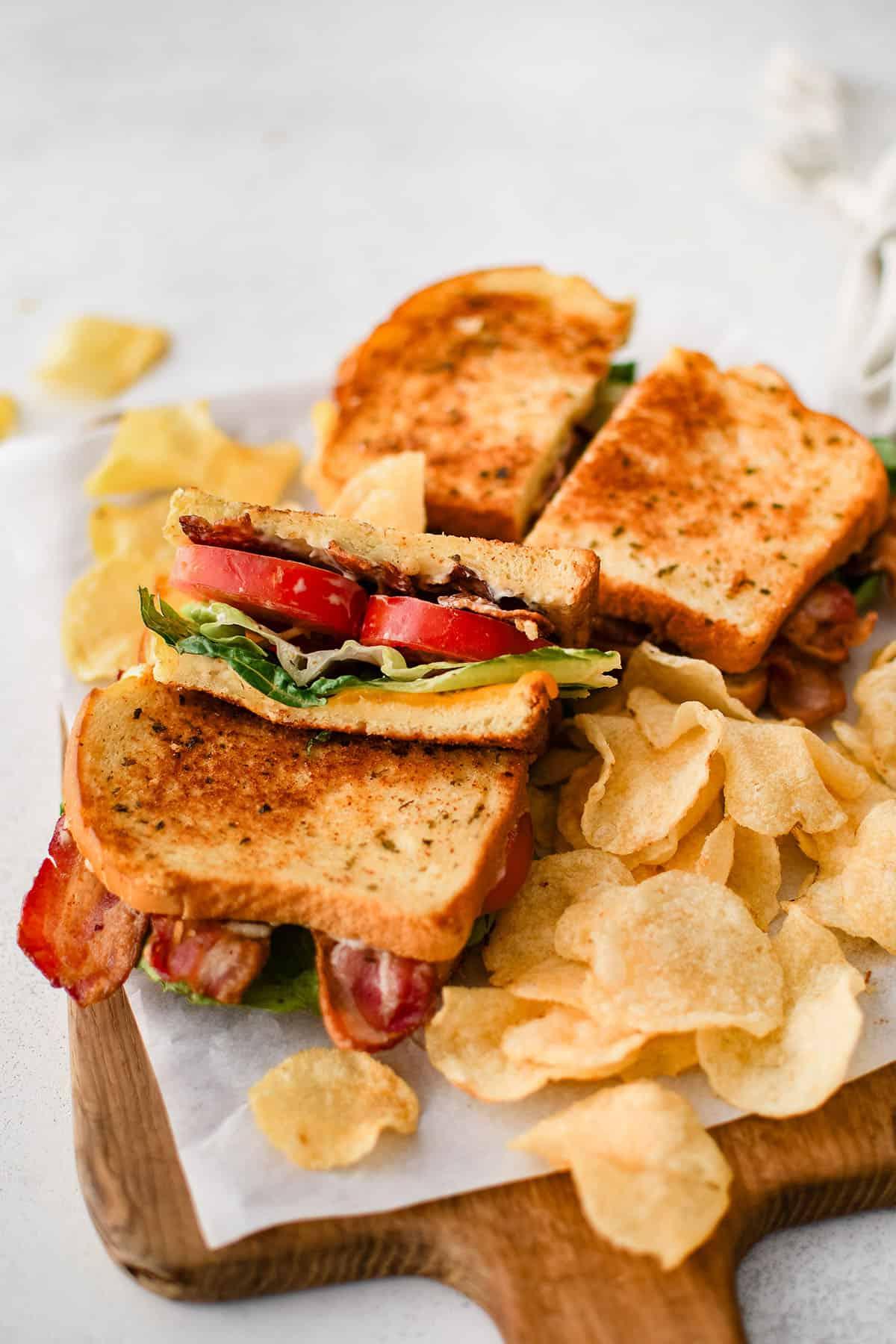 Due panini BLT su un piatto con patatine