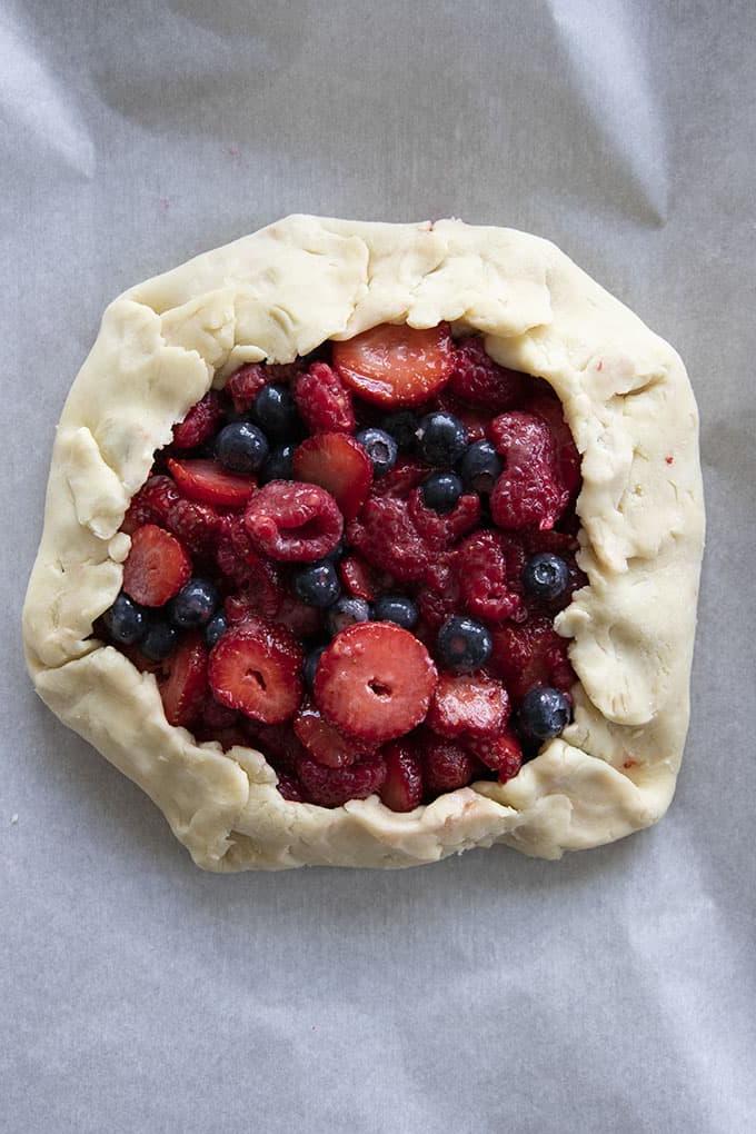 Galette di frutta pronta per essere infornata, con i bordi ripiegati e il ripieno a vista