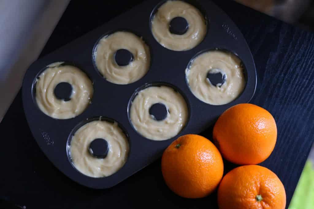 Teami di ciambelle riempiti per due terzi con l'impasto, pronti per la cottura.