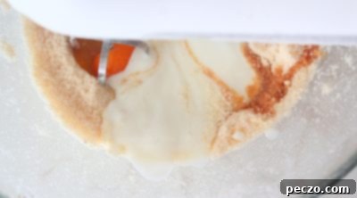 Wet ingredients being added to cake batter and mixed