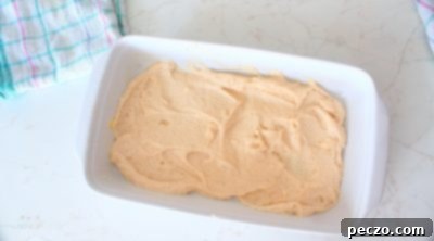 Half of the cake batter spread in the baking pan