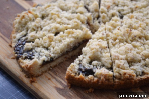 A beautifully rustic Torta Sbrisolona, an Italian crumb cake, featuring a golden-brown, crumbly texture with visible almond pieces. It's presented as a large, round dessert, inviting to be broken by hand, embodying the traditional charm of homemade Italian sweets. Perfect for a cozy dessert, it highlights the simple elegance of this timeless recipe.