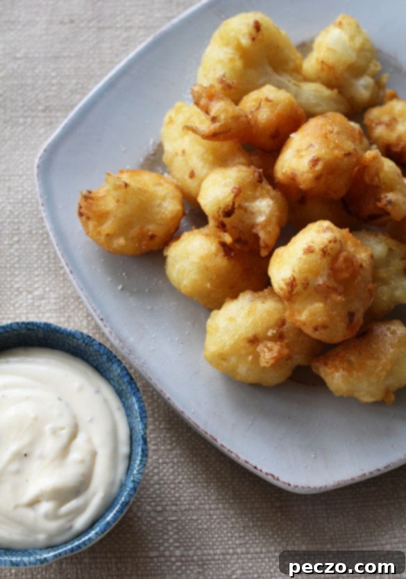A close-up of crispy, golden cauliflower fritters perfectly cooked and ready to be served, highlighting their texture.