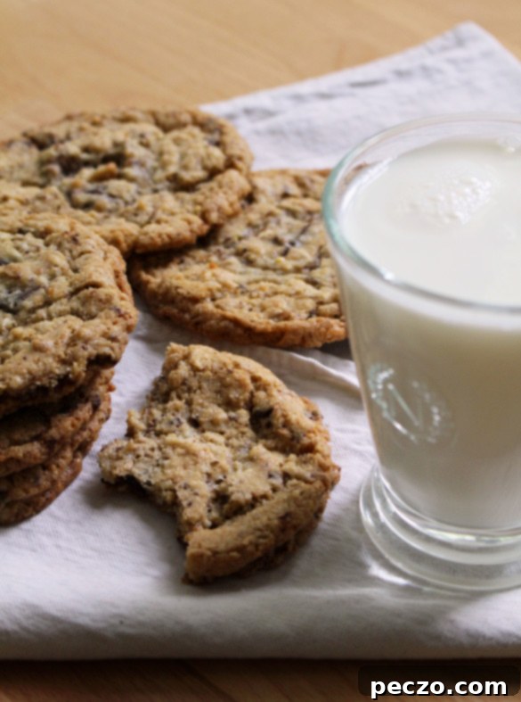 A freshly baked batch of Mona's Mother's Best Friend's Favourite Oatmeal Chocolate Chip Cookies cooling on a wire rack, with some arranged on a rustic plate, inviting and warm.