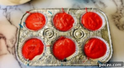 Layering red cupcake batter on top of white batter
