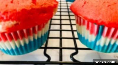 Baked red, white, and blue layered cupcakes cooling on a rack