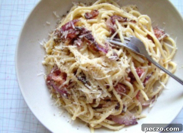 Delicious plate of creamy Spaghetti Carbonara with crispy guanciale and grated cheese