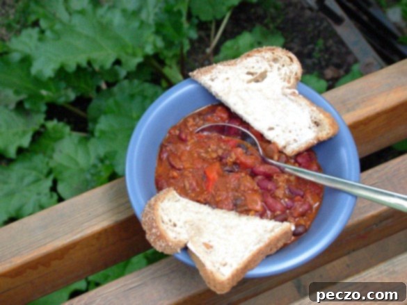 Hearty homemade chili with sliced buttered bread on a rustic wooden table