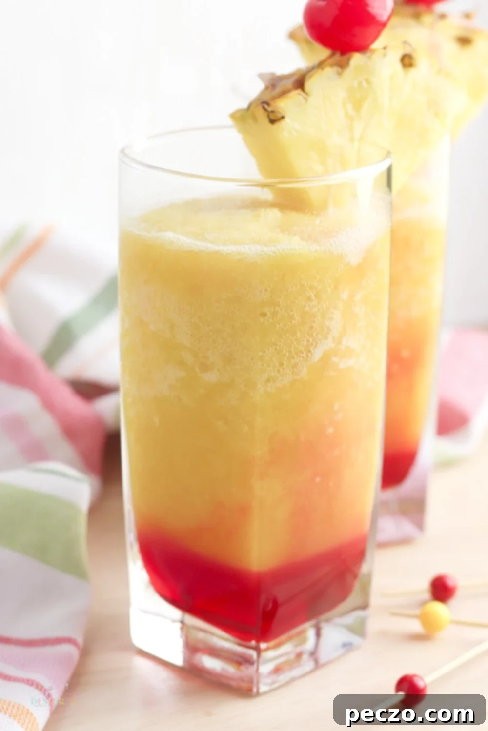 A glass of Bahama Mama drink garnished with pineapple and cherries