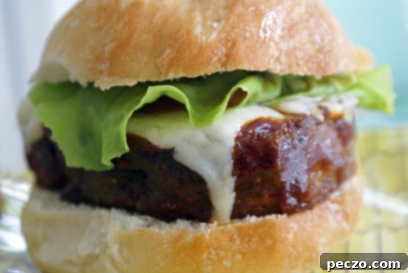 Juicy grilled meatloaf burger on a sesame bun with melted cheese, lettuce, and tomato
