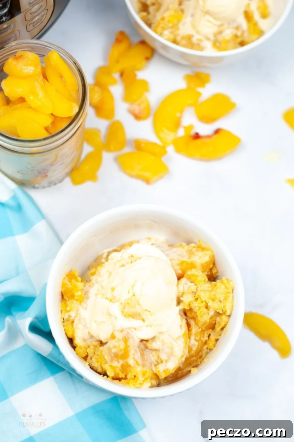 Image of instant pot peach cobbler in a white bowl, topped with vanilla ice cream
