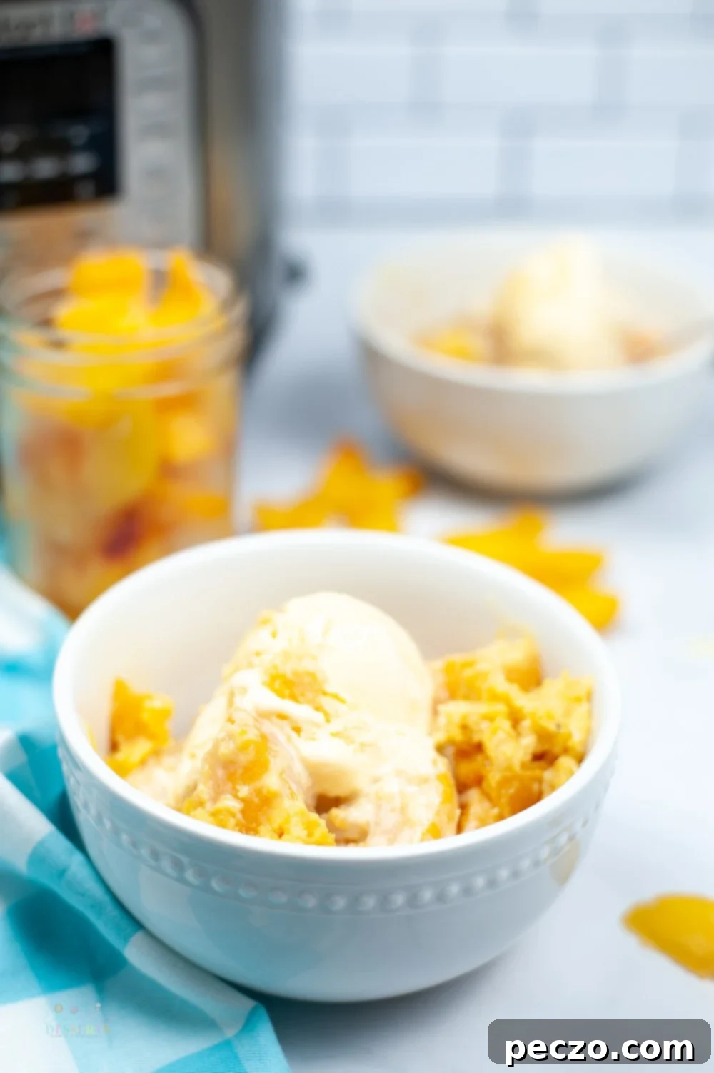 Side image of peach cobbler in a white bowl, topped with vanilla ice cream