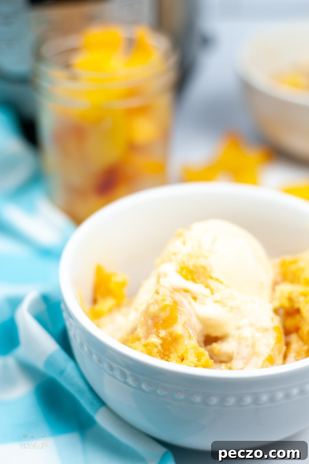 Side image of instant pot peach cobbler in a white bowl, topped with vanilla ice cream