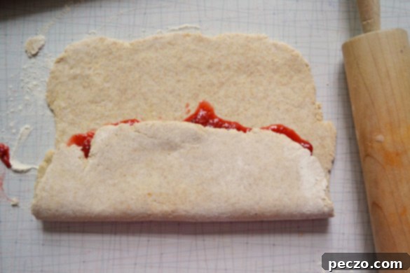 Scone dough folded into thirds, resembling a letter, with the strawberry rhubarb filling enclosed.