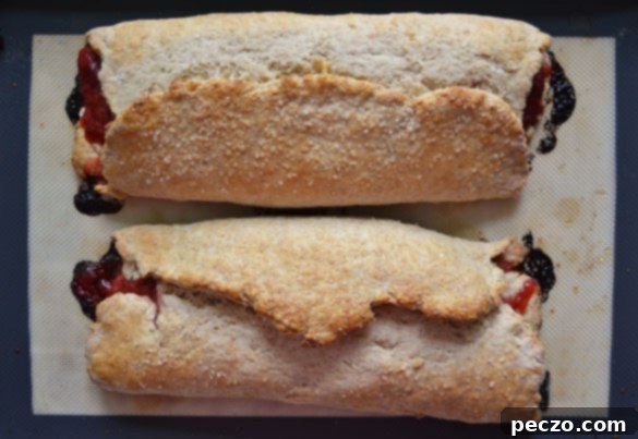 Two freshly baked strawberry rhubarb slab scones, golden and puffed, cooling slightly on a wire rack.