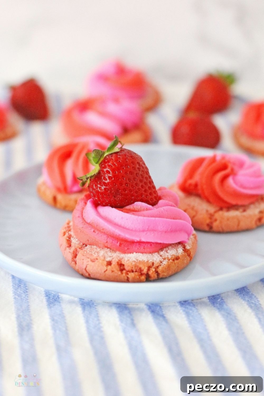 Image of fluffy strawberry cookies decorated with swirl cream cheese frosting and fresh strawberry slices on a white serving plate