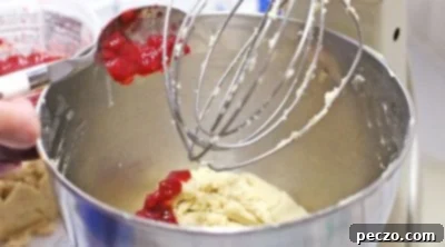Strawberry cookie dough being mixed in a stand mixer, showing a vibrant pink color