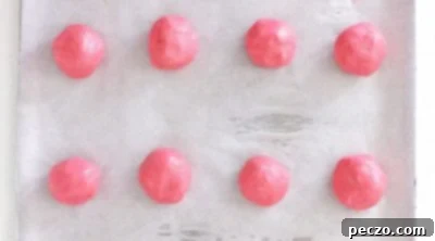 Strawberry cookie dough balls ready for baking on parchment paper