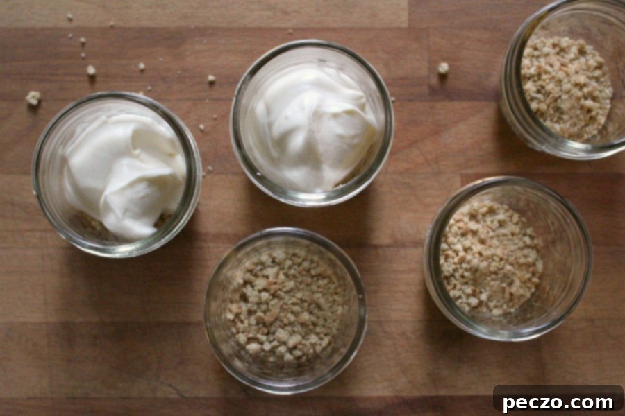 A close-up of a no-bake cheesecake jar, showing the layered crust, creamy filling, and fresh cherry topping.