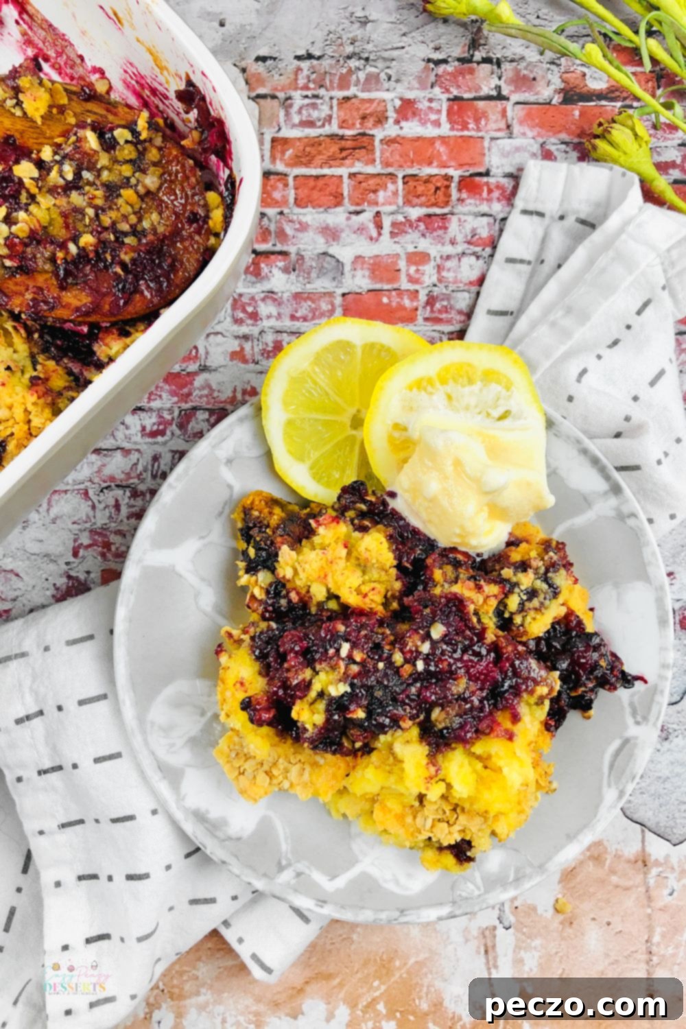 Blackberry dump cake on a white serving plate, next to a baking dish filled with the same cobbler