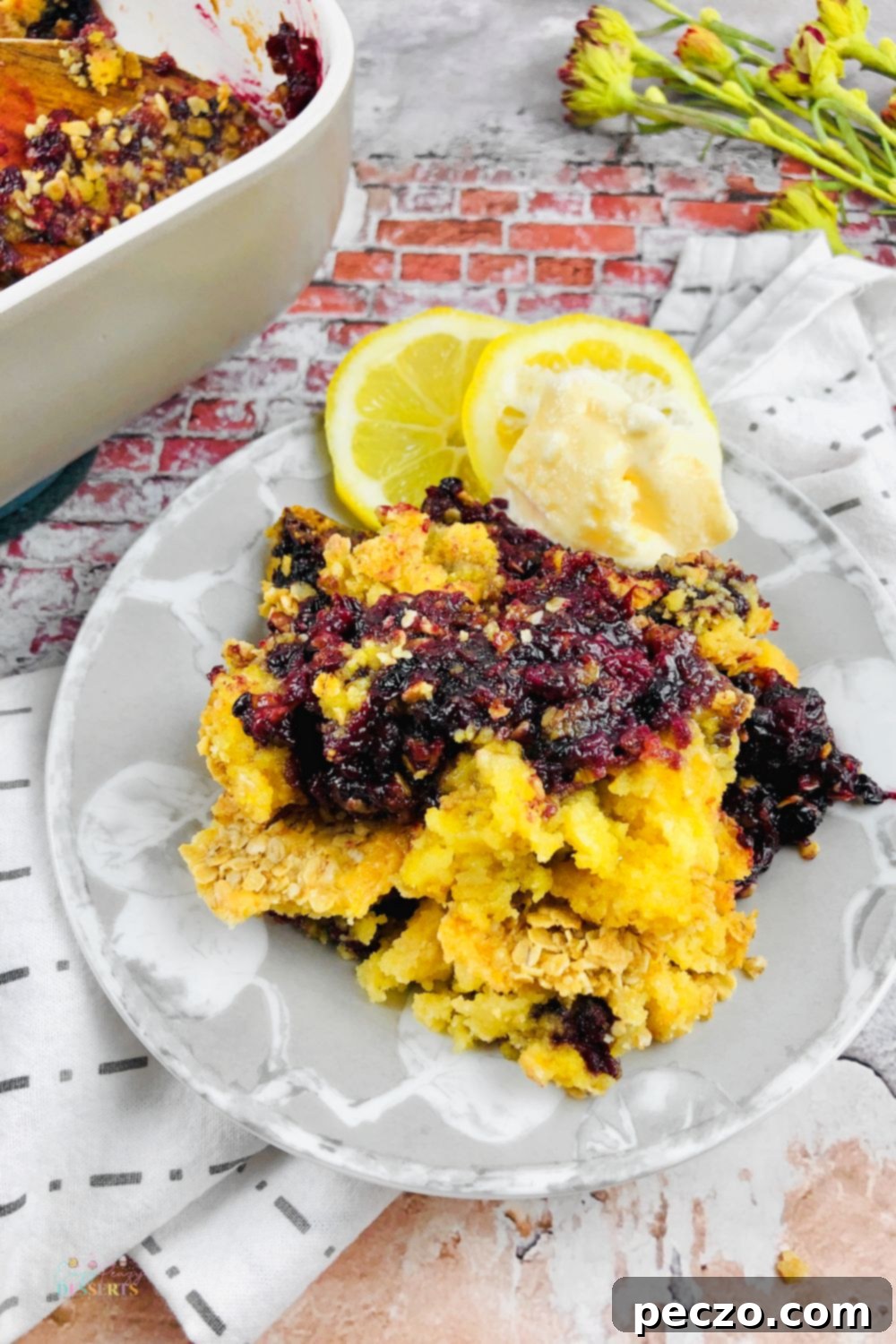 Image of blackberry cobbler with cake mix on a serving plate, placed next to a baking dish filled with the rest of the cake