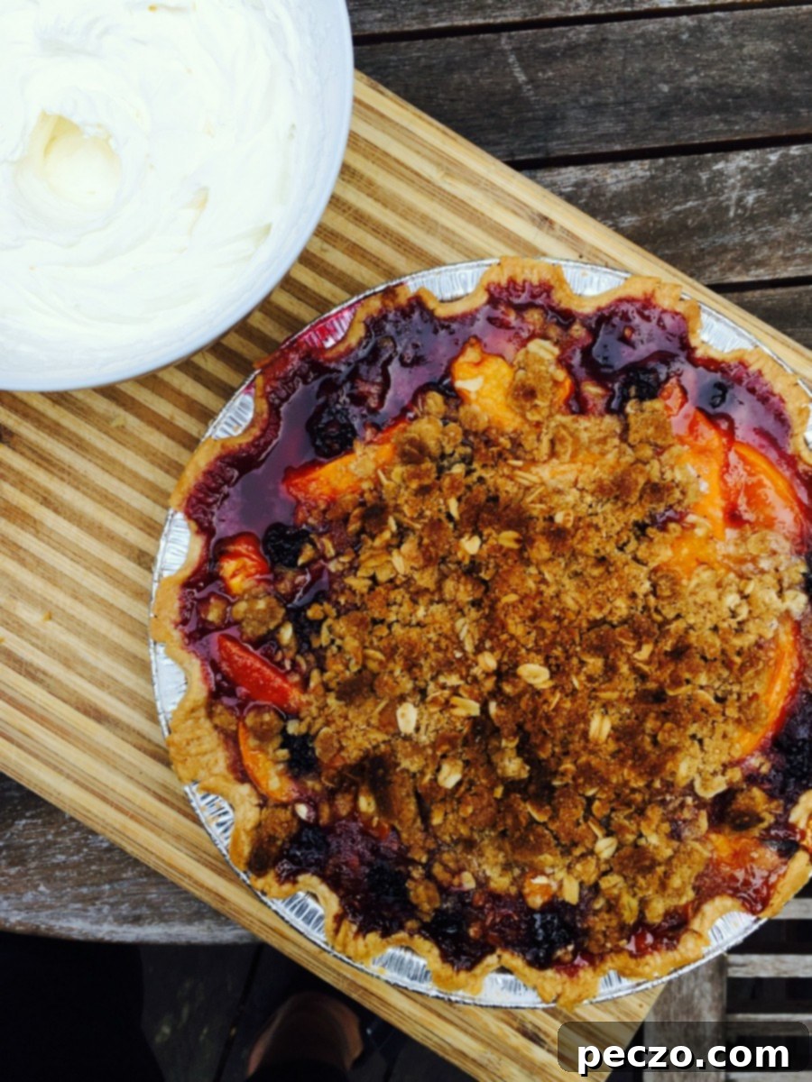 A slice of stone fruit crumble pie with whipped cream