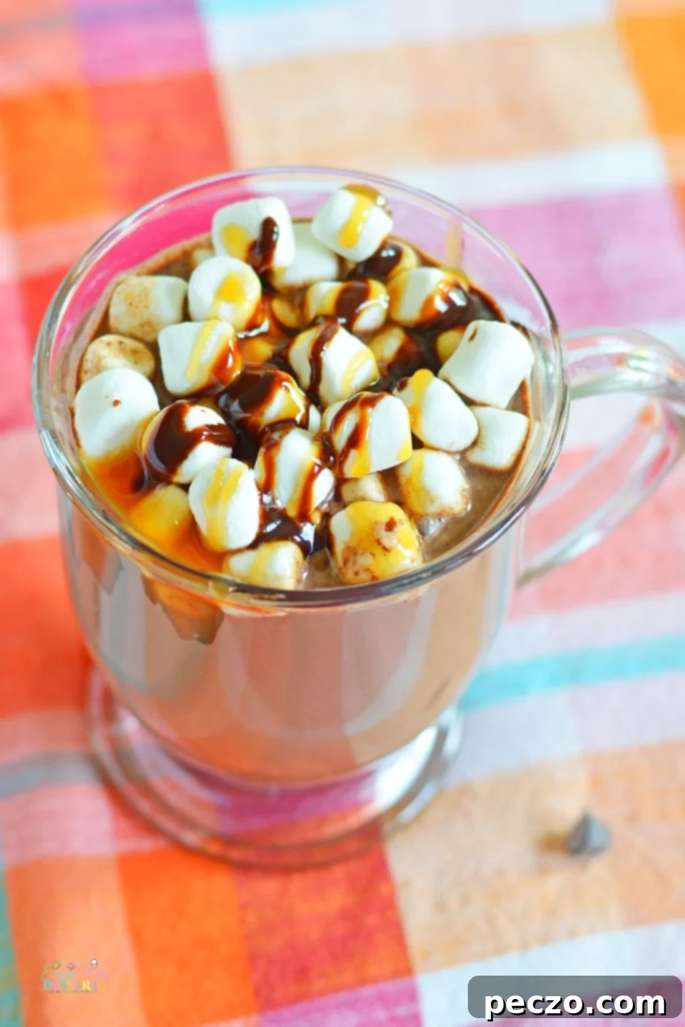 A hand pouring caramel vodka into a saucepan of hot chocolate