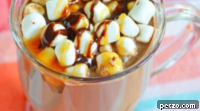 Boozy hot chocolate in a mug, decorated with marshmallows and chocolate caramel syrup