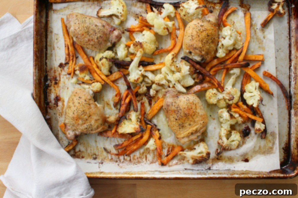 Golden brown sheet pan chicken thighs and colorful roasted vegetables ready to serve