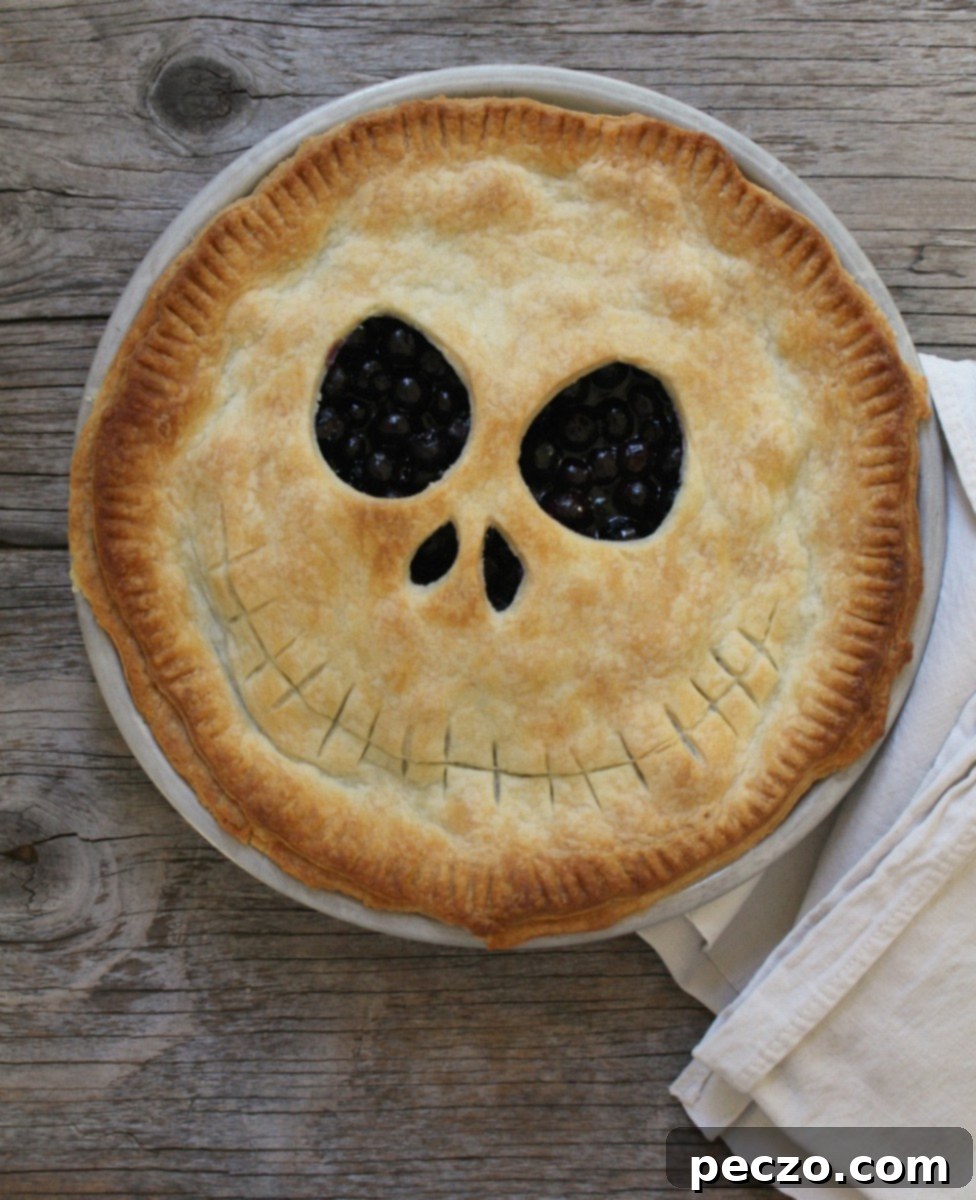 A stunning Jack Skellington pie, featuring a spooky face carved into the top crust and a dark berry filling peeking through.
