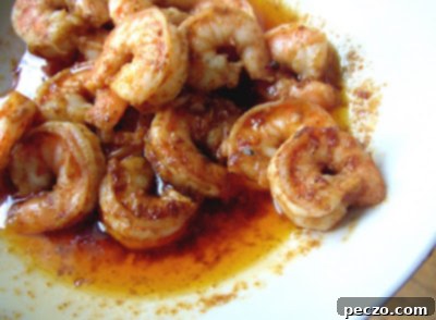 Close-up of perfectly cooked barbecue shrimp in a pan, coated in spicy butter sauce