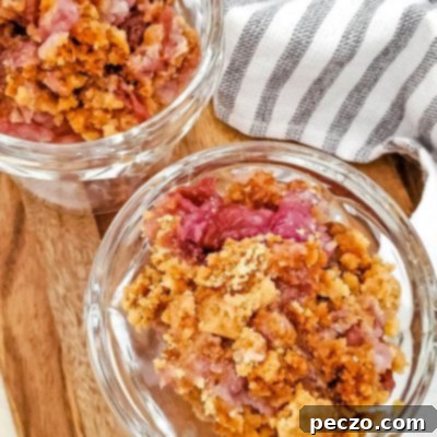 Easy Cherry Pineapple Dump Cake 7 Two dessert cups filled with pineapple cherry dump cake, sitting on a cutting board next to a kitchen towel