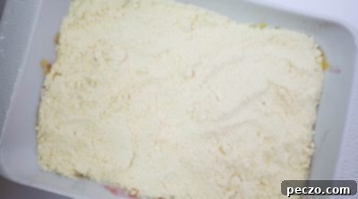 Dry yellow cake mix poured over fruit in a baking pan