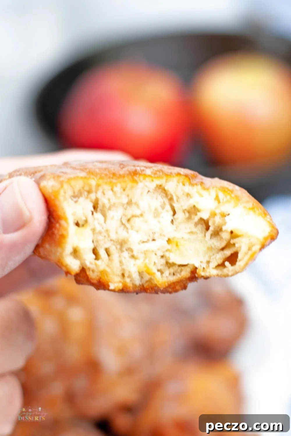 Detailed cross-section image of a homemade fried apple fritter, showcasing the tender apple pieces and fluffy dough texture