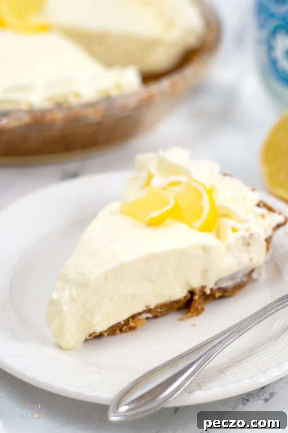 Image of a slice of lemon pie in a serving plate, decorated with a slice of lemon