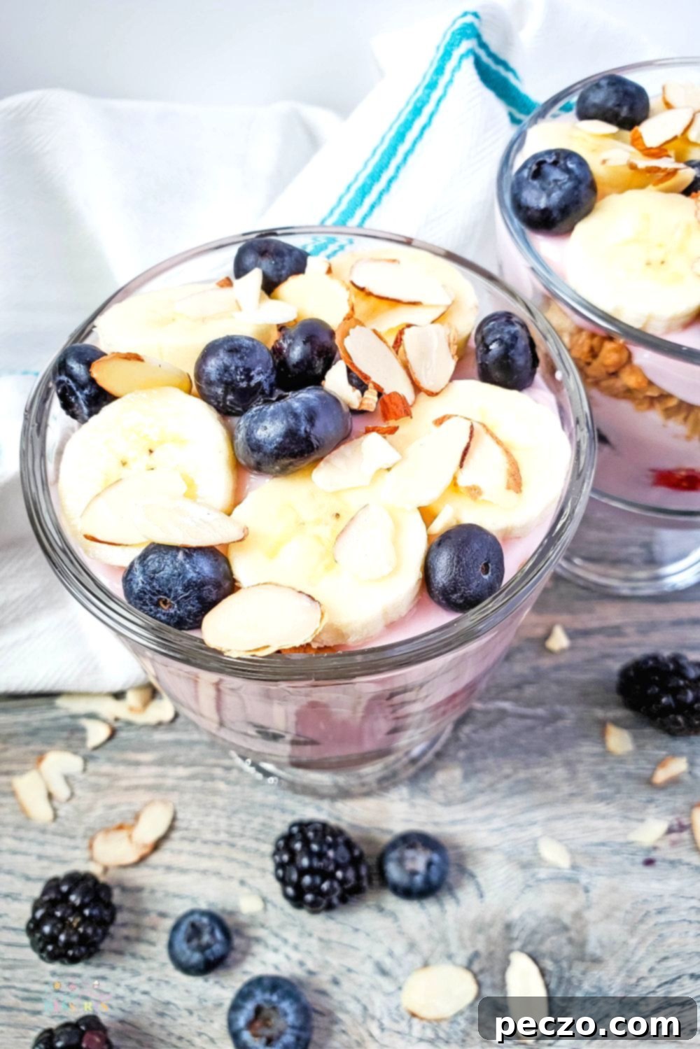 Angle image of triple berry trifle in a cup, showcasing layers and fresh fruit topping.