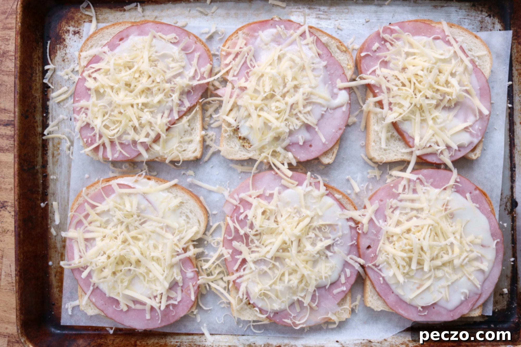 Croque Monsieur sandwiches with béchamel sauce on a sheet pan