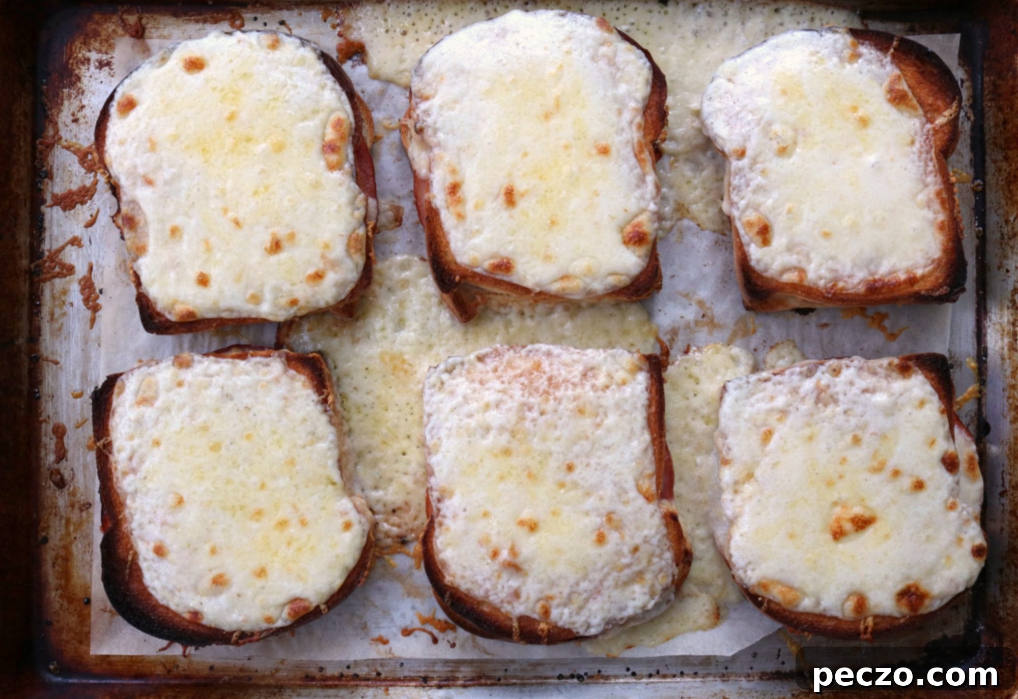 Four finished Croque Monsieur sandwiches on a sheet pan, ready to serve
