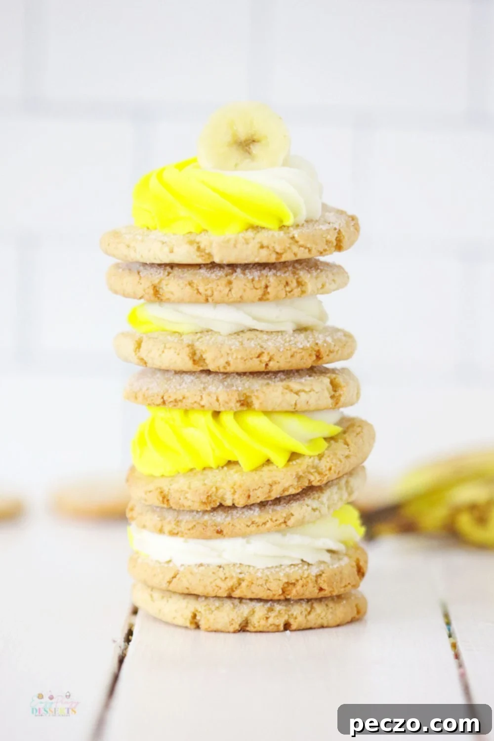 Close up image of a stack of banana cookies with white and yellow cream cheese frosting
