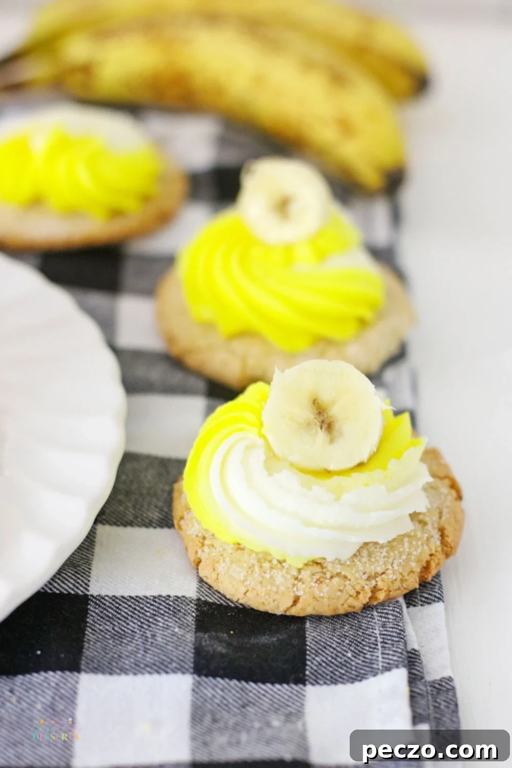 Image of two banana bread cookies decorated with cream cheese frosting and a slice of banana