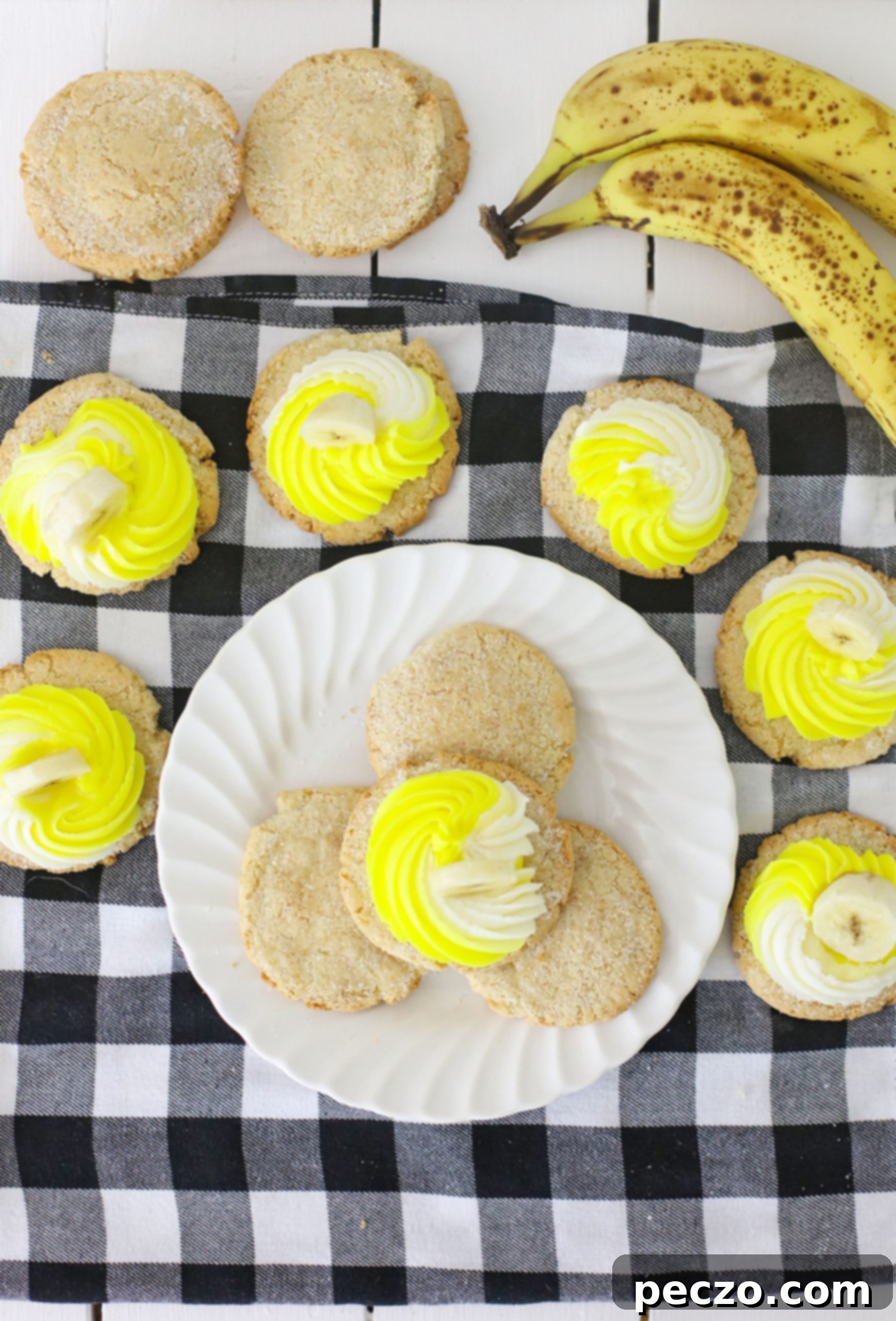 Overhead image of banana cookies decorated with white and yellow cream cheese frosting and banana slices