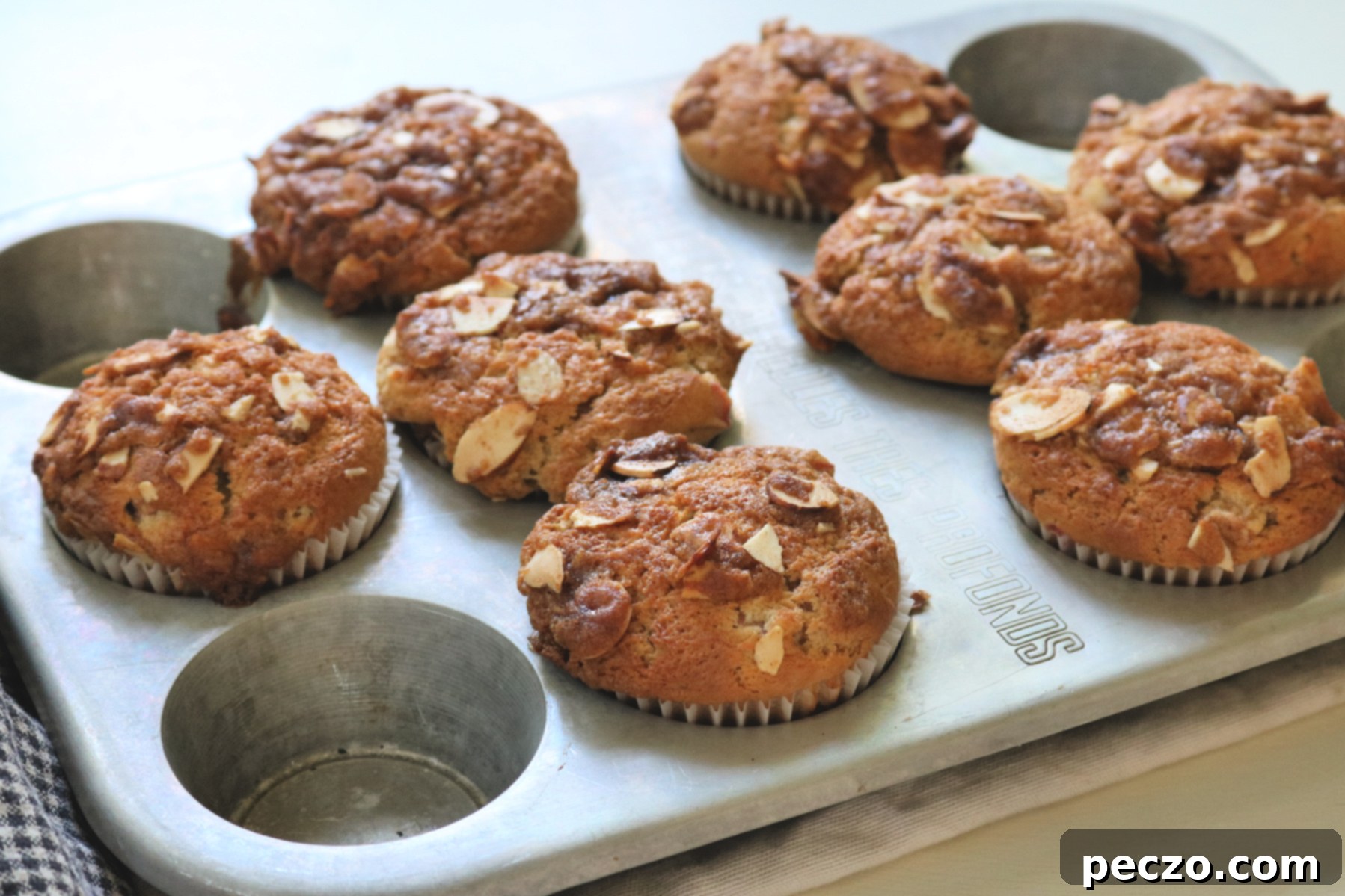 Two Phantom Rhubarb Muffins on a plate, with one broken open to reveal its moist interior, chunks of rhubarb, and fluffy texture.