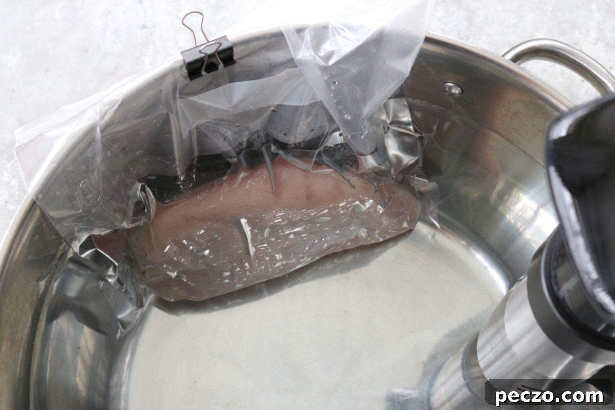 An Anova Sous Vide precision cooker submerging in a water bath, ready to cook turkey.
