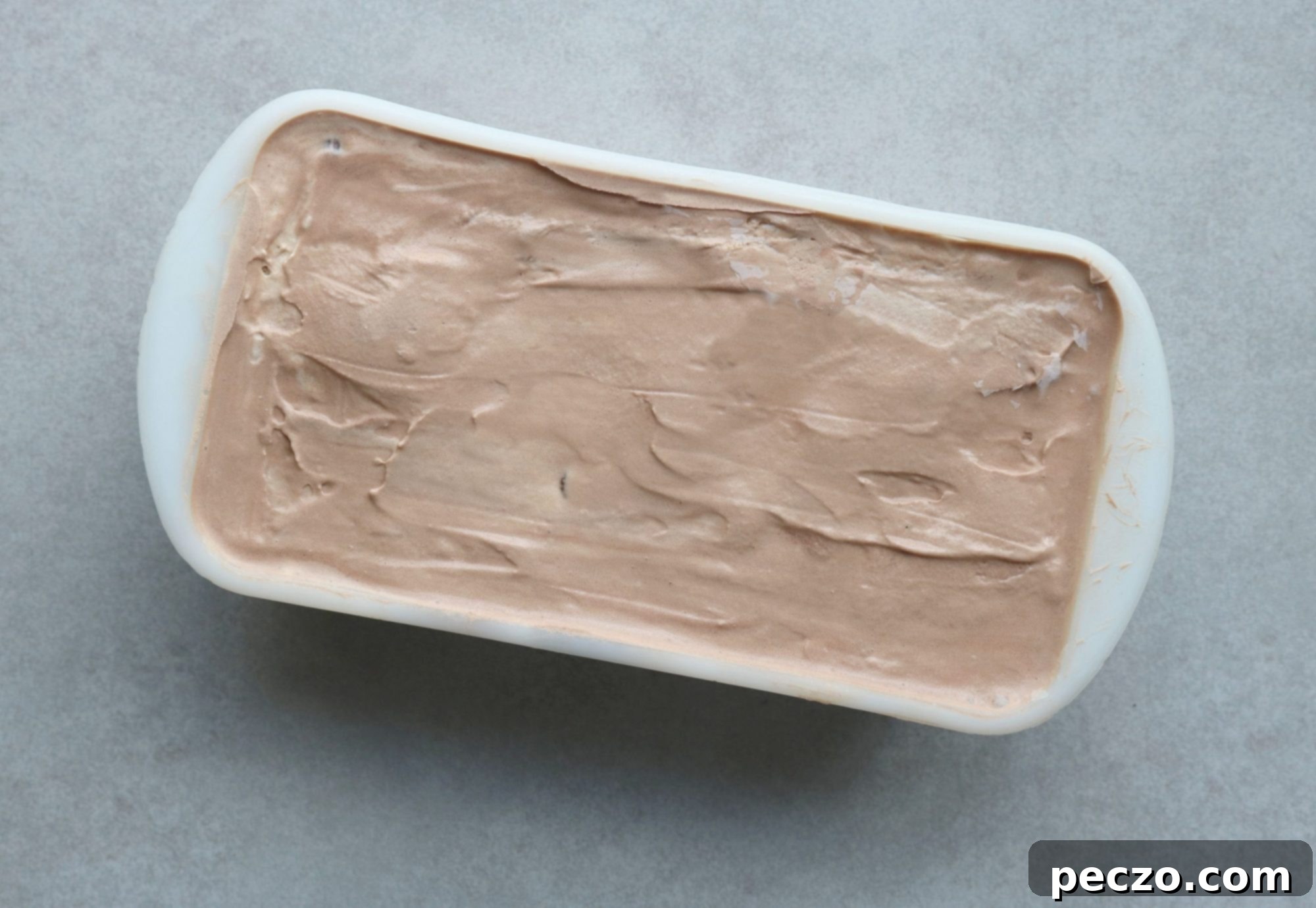 Preparing the ice cream cake base, showing scoops of different ice cream flavors being layered in a pan