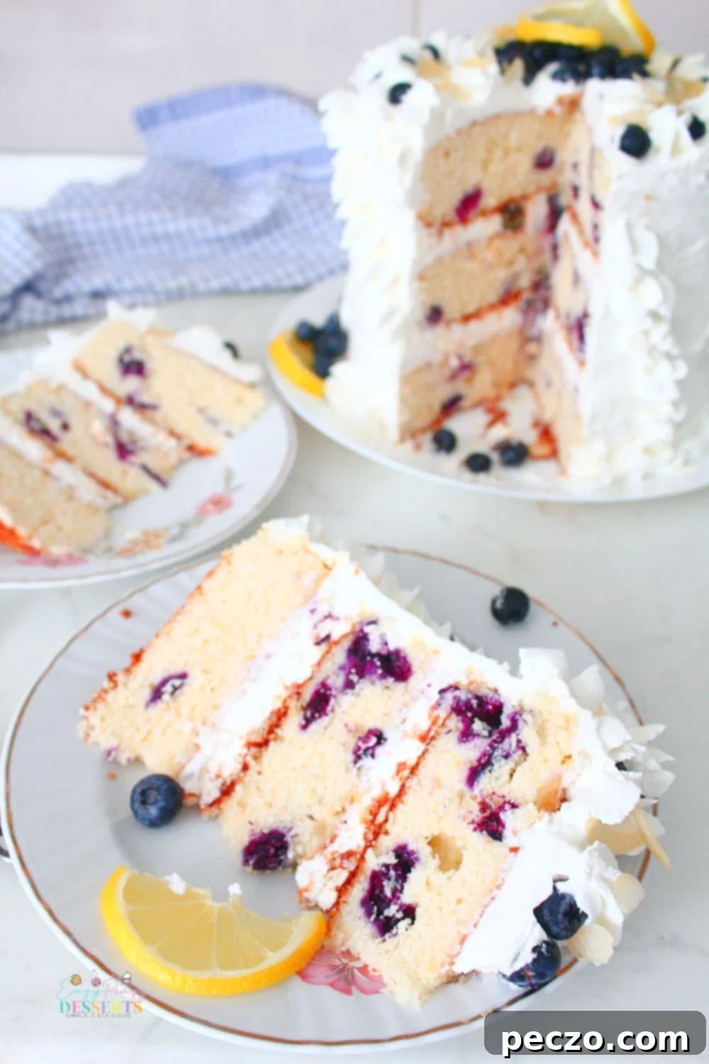 A slice of lemon and blueberry cake decorated with lemon and fresh blueberries