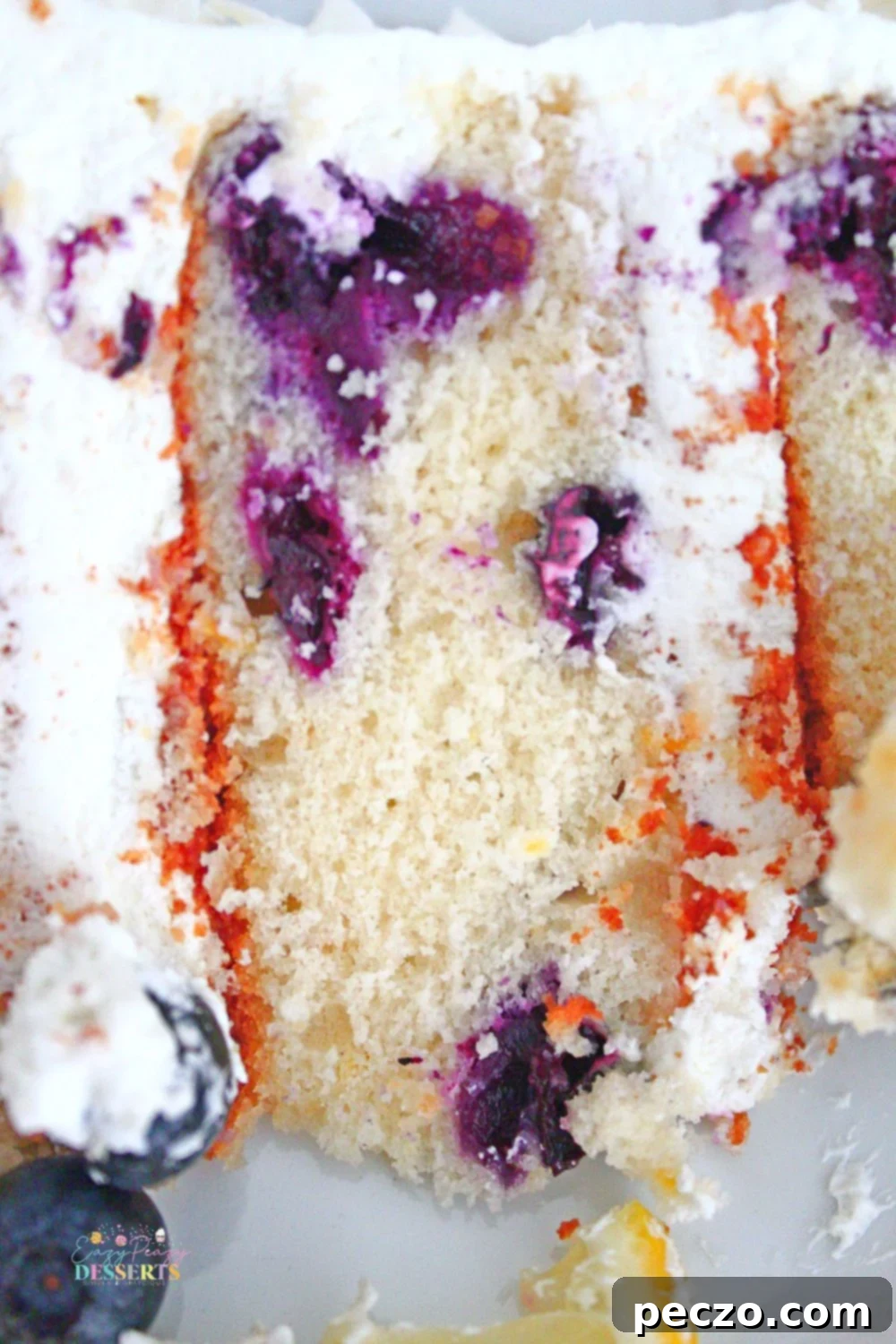 Close up image of an entire lemon blueberry cake with frosting and berries