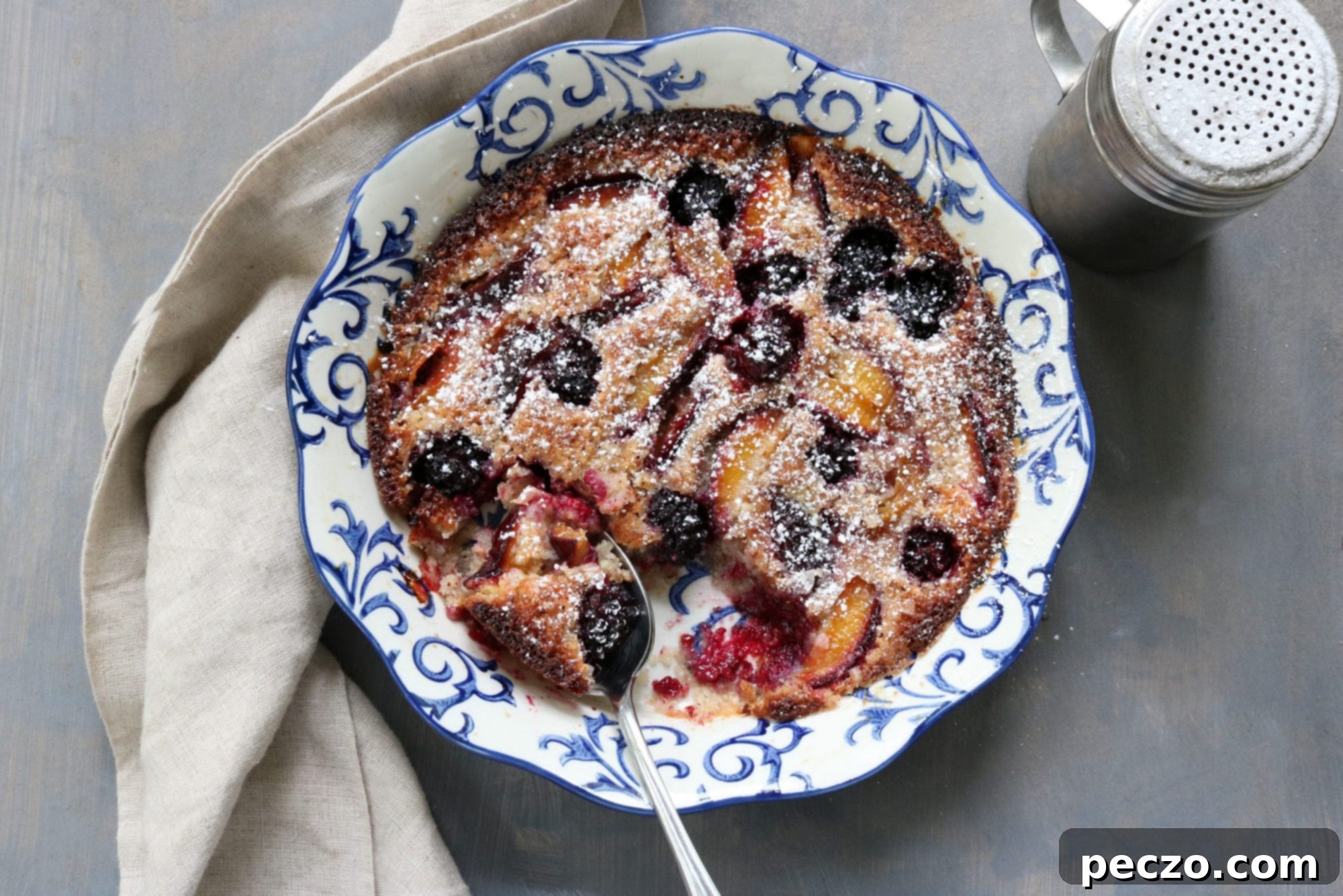 Deliciously baked blackberry plum friand in a baking dish, with a golden crust and visible fruit