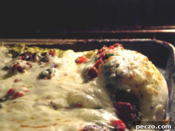 Close-up of a vibrant pesto pizza topped with chicken sausage, spinach, and mozzarella, fresh out of the oven.